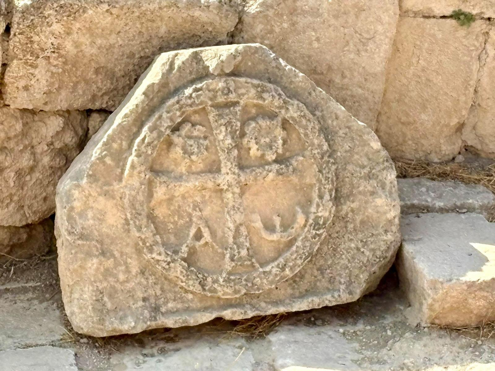 An ancient carved stone incised with a cross and the Greek letters alpha and omega.
